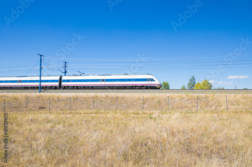 locomotive of fast speed train on railway in a landscape with blue sky in countryside of Spain, Europe 