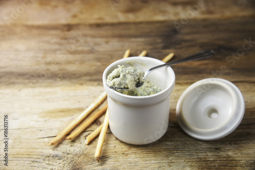 potted blue stilton cheese on a spoon and in a ceramic jar, some nibbles sticks on a rustic wooden table, copy space