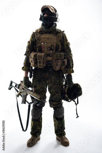Full length portrait of serious peacemaker holding helmet and modern weapon in arms. Army concept
