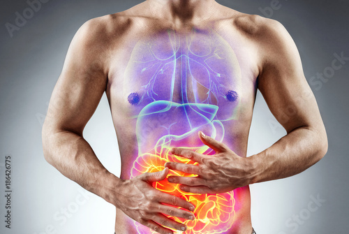 Man holding his stomach in pain. Photo of man with naked torso experience irritable bowel syndrome on grey background. Medical concept