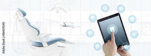 dentist hand touch digital tablet screen teeth icons and symbols on dental clinic with dentist's chair background web banner template contact us concept