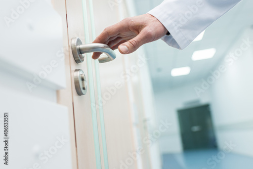 cropped view of male doctor holding door handle in hospital