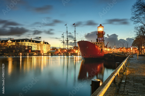 Lightship moored at the quay with in the background the Maritime Museum with VOC ship in Amsterdam
