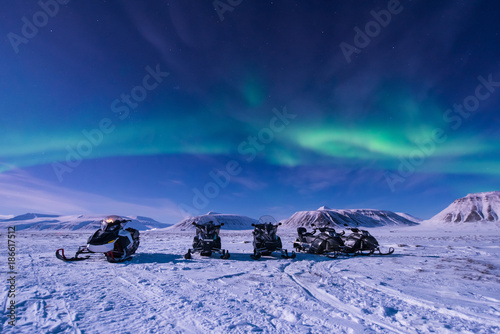 The polar arctic Northern lights aurora borealis sky star in Norway Svalbard in Longyearbyen city snowmobile the moon mountains