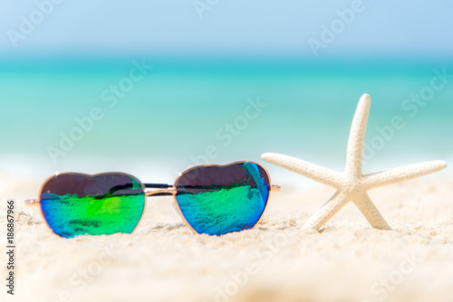Summer Fashion heat shape sunglasses on sea beach under clear blue sky. Summer holiday relax background, copy space.