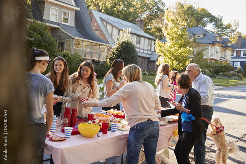 Neighbours talk standing around a table at a block party