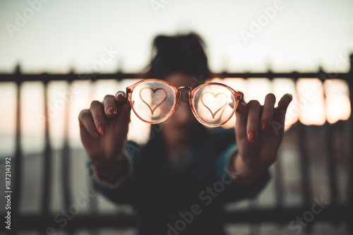 Simbolo del Cuore sugli occhiali di vetro appannato tenuti in mano da una ragazza.
