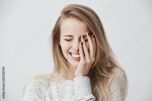 Positive emotions concept. Beautiful happy Caucasian blonde woman dressed casually smiling broadly, showing her perfect white teeth, relaxing, closing eyes because of joy, spending weekend indoors
