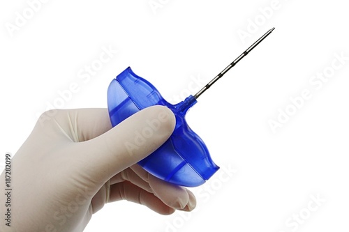 Bone marrow biopsy needle held in doctor left hand in sterile powdered latex glove, white background