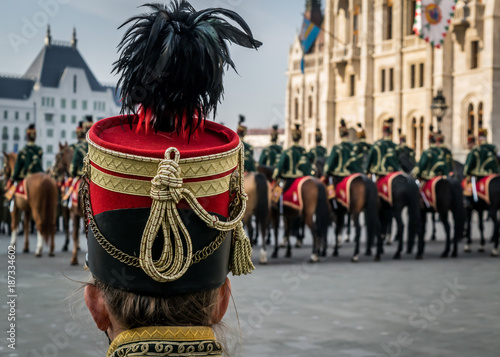 Hussar traditional military hat closeup. Background with line up of hussar cavalry on horses in front of the Parliament House during the 15 March military parade in Budapest, Hungary. 