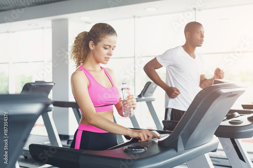 Man and woman, couple in gym on treadmills