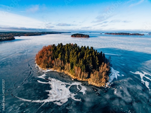 Aerial view of the winter snow forest and frozen lake from above captured with a drone in Finland.