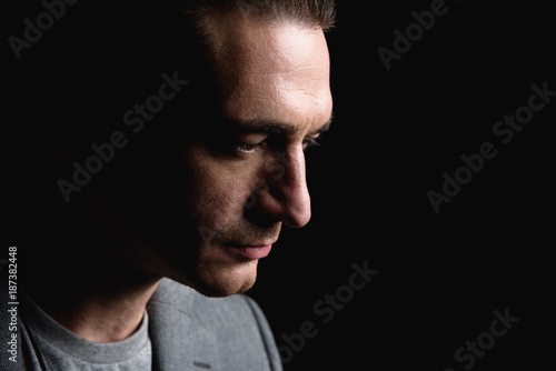 Feeling hopeless. Close-up profile of sad stylish young man is standing and looking down wistfully. Isolated background with copy space in the right side