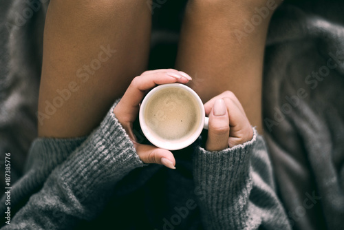 girl in bed holding cup of coffee drinks