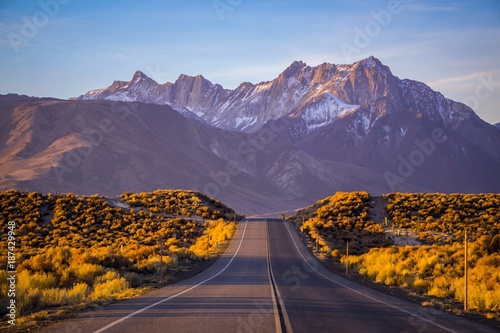 A road in Eastern Sierra leading up to a beautiful snow coverred mountain with morning light
