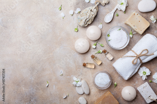 Spa setting from body care and beauty threatment products with flowers on stone background top view. Healthy and wellness concept. Flat lay.