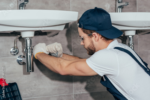 close-up view of young professional plumber fixing sink in bathroom