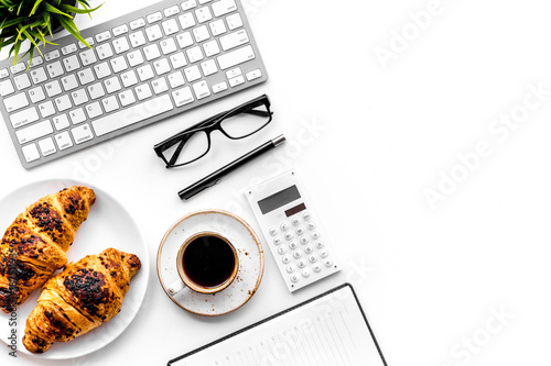 Business breakfast. Small cup of coffee and croissants on office desk. White background top view copy space