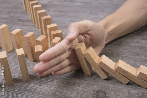 hand stopping wooden block domino. concept prevent and solution.