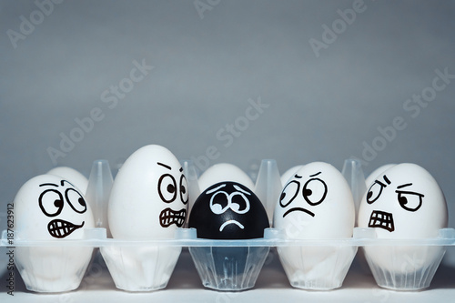 Faces on chicken eggs in the form of facial expressions, reflecting emotions. The concept of racism, misunderstanding, a barrier in relations, denial of society. Barriers between people, prejudice.