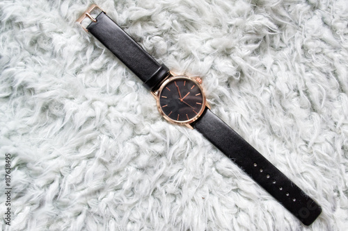 Black wristwatch on gray fur. Fashionable concept