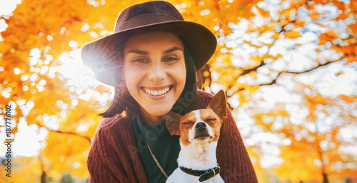 Portrait of happy young woman with dog outdoors in autumn