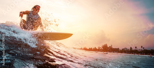 Surfer jeździ na fali oceanu podczas zachodu słońca. Pojęcie sportu ekstremalnego i aktywnego stylu życia