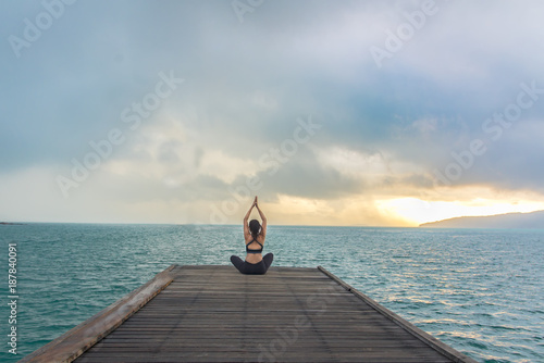 Healthy woman lifestyle balanced practicing meditate and energy yoga on the wood bridge in morning the beach. Healthy Concept..