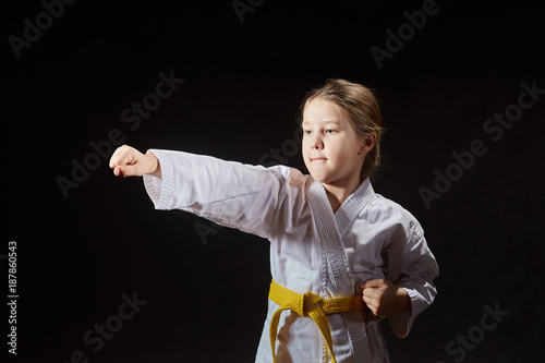 In karategi the sportswoman is beating blow hand against a black background