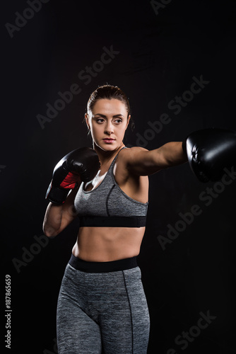 sporty athletic young woman boxing isolated on black