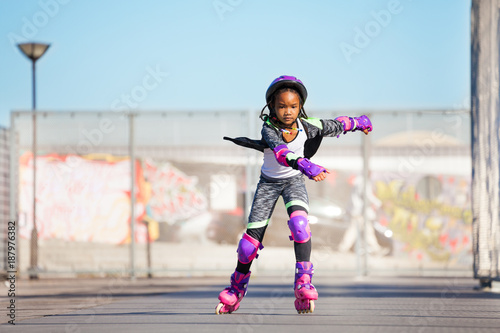 African girl rollerblading fast at skate park