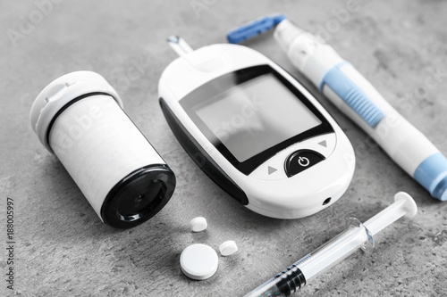Digital glucometer, lancet pen, syringe and medicaments on grey background. Diabetes management