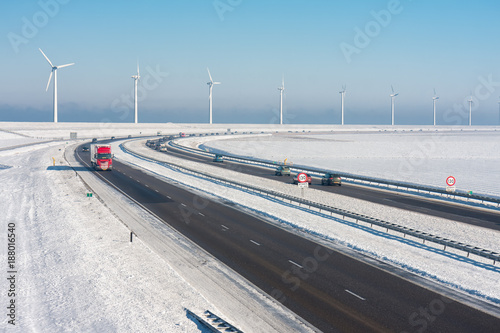 Dutch winter landscape with highway along wind turbines against a blue sky