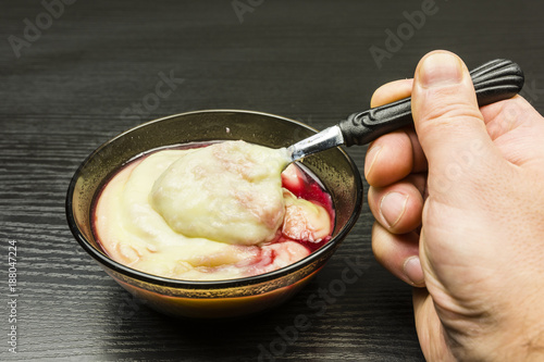 Teaspoon with pudding and raspberry juice from a bowl.