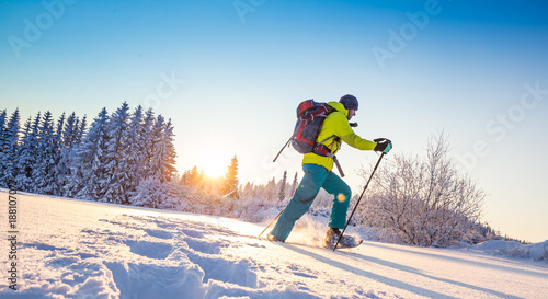 Sunny winter landscape with man on snowshoes.