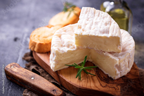 Camembert cheese with rosemary on wooden board