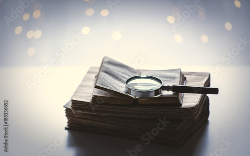 Books and magnifier on table with fairy lights