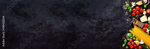 Food ingredients for italian pasta, spaghetti on black stone slate background. Copy space of your text. Banner