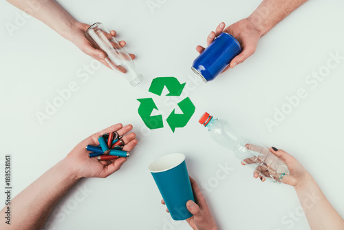 partial view of people showing various types of garbage around recycle sign isolated on grey