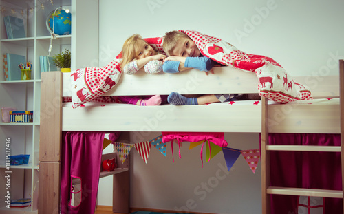 Two happy sibling children having fun in bunk bed