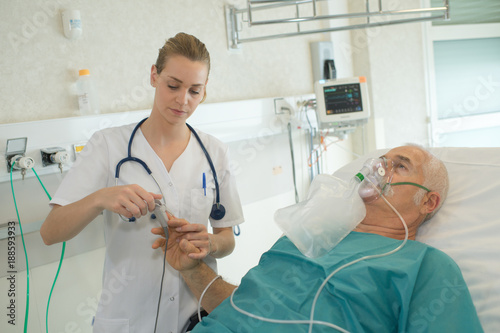Nurse attaching pulse monitor to elderly patient