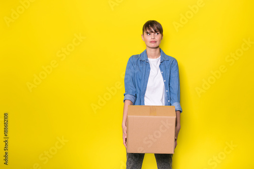 isolated woman on yellow with cardboard box