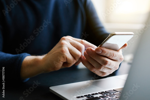 Man with a finger on the screen using a mobile phone in the office