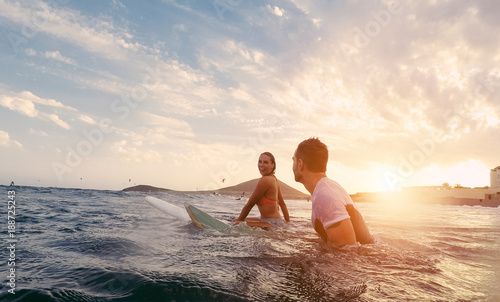 Fit couple surfing at sunset