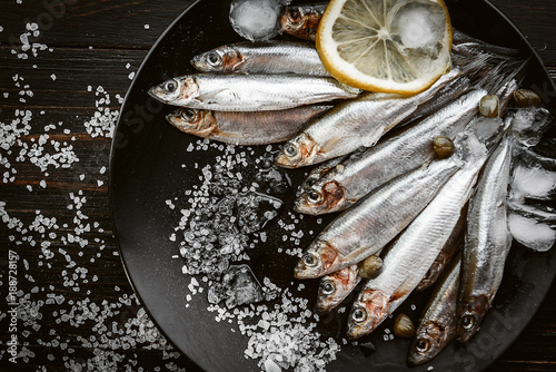 raw fresh fish on a plate with salt and lemon in a rustic style on a wooden surface