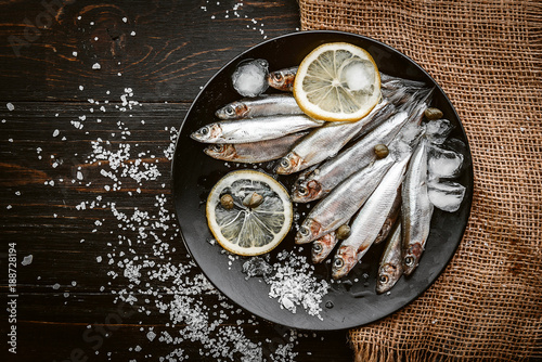 raw fresh fish on a plate with salt and lemon in a rustic style on a wooden surface