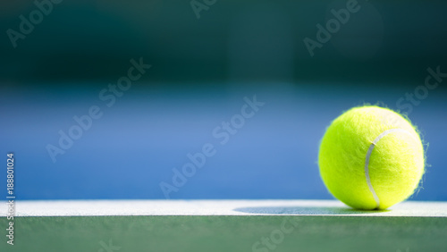 jedna nowa piłka tenisowa na białej linii w niebieskim i zielonym twardym korcie ze światłem z prawej strony, cieniem i miejscem do kopiowania po lewej stronie