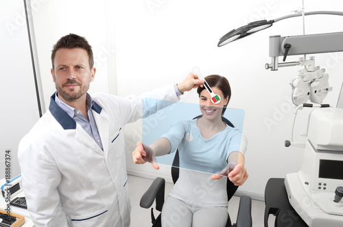 optometrist examining eyesight, woman patient pointing at the hole on plexiglass, ocular dominance test