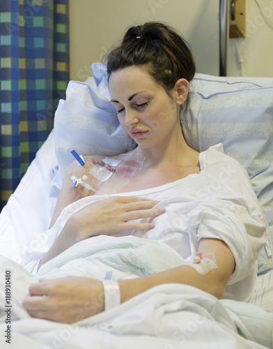 Sick young woman laying in hospital bed with Central Venous Catheter (CVC) being administered fluids and Parenteral Nutrition (PN)