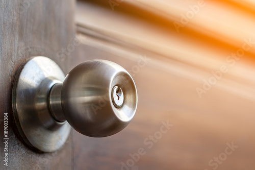 stainless door knob and keyhole on old wooden door with sunlight effect, shallow depth of field